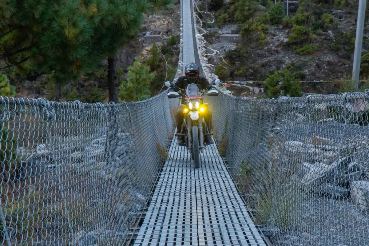 Rider crossing a suspension bridge on the way to Manang
