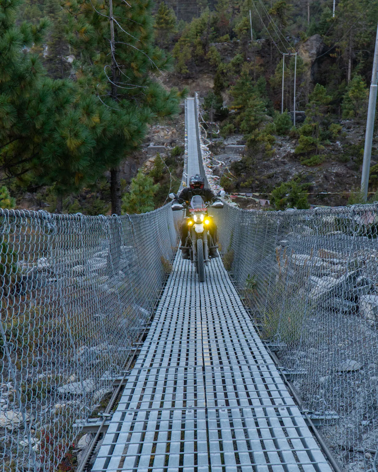 Rider crossing a suspension bridge on the way to Manang